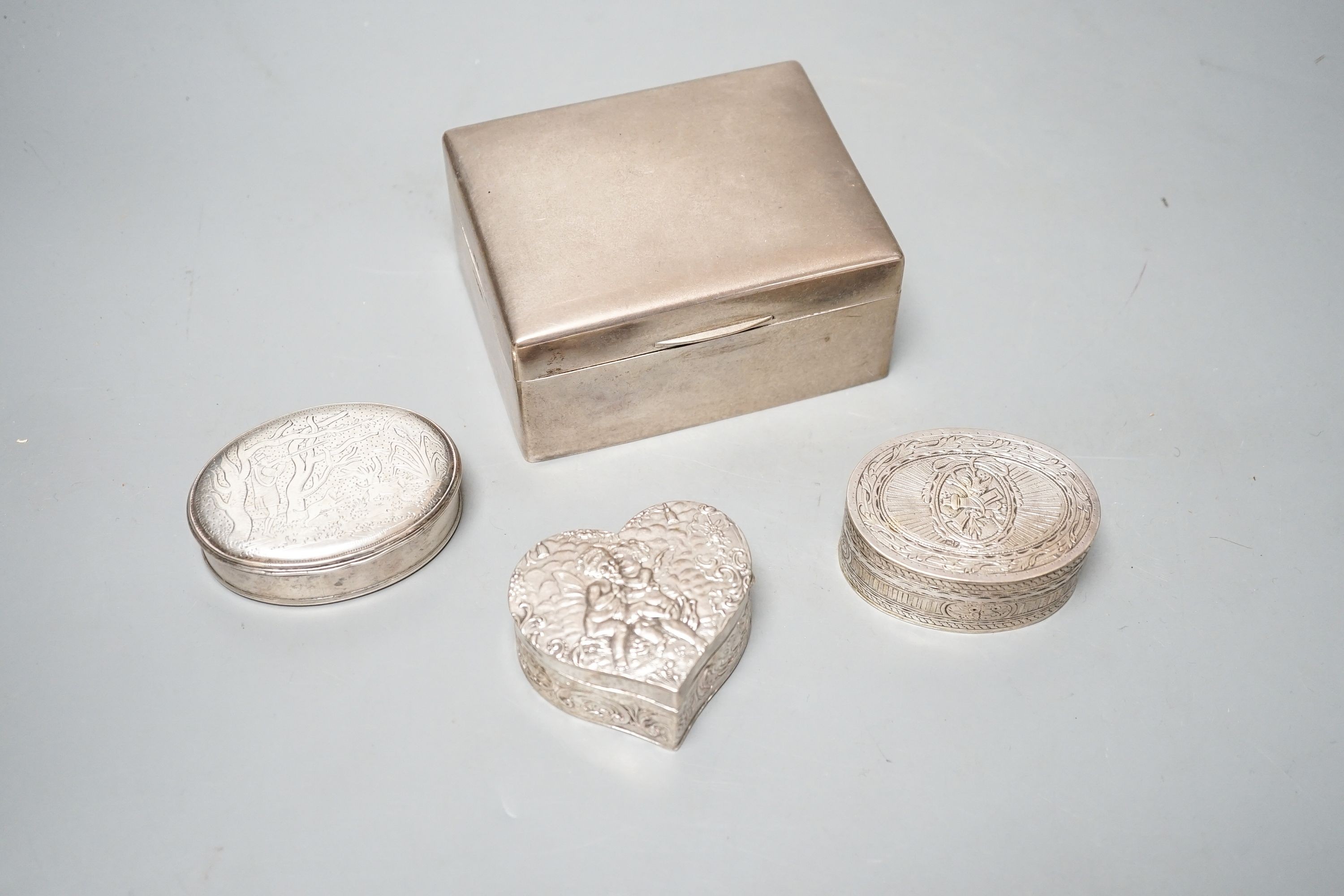 A continental oval white metal snuff box, engraved with hunting scenes, 72mm, a silver oval snuff box with Sheffield, import marks, a silver heart shaped box and a silver cigarette box.